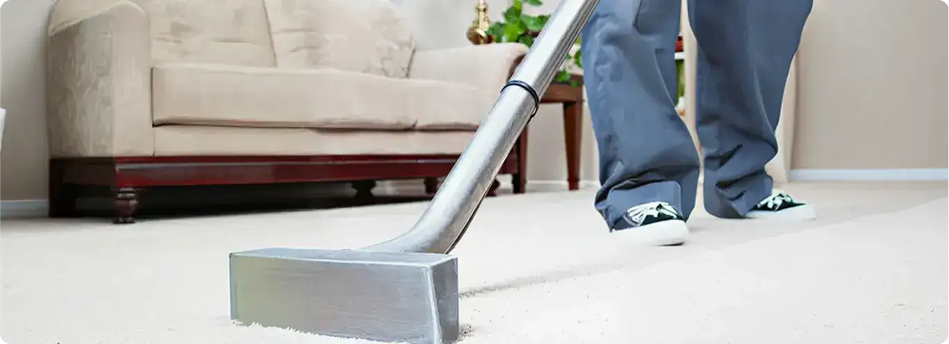 Carpet cleaning technician using a hot-water extraction wand on a light-colored carpet in a living room, Dover, DE.