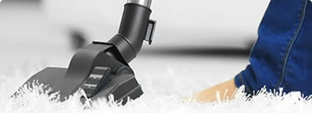 Close-up of a professional vacuuming a white carpet in Camden Wyoming.