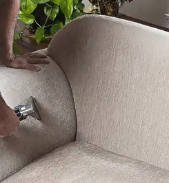 Professional upholstery cleaner deep-cleaning a fabric sofa with a handheld extraction tool and hose Dover, DE.